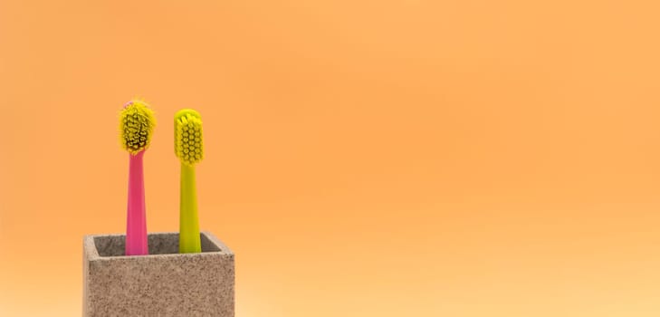 Banner Used Old And New Toothbrush On Peach Yellow Background, Empty Space For Text. Replace Old Toothbrush With A New. Personal Oral Hygiene Set. Old And New Toothbrushes Horizontal Plane.