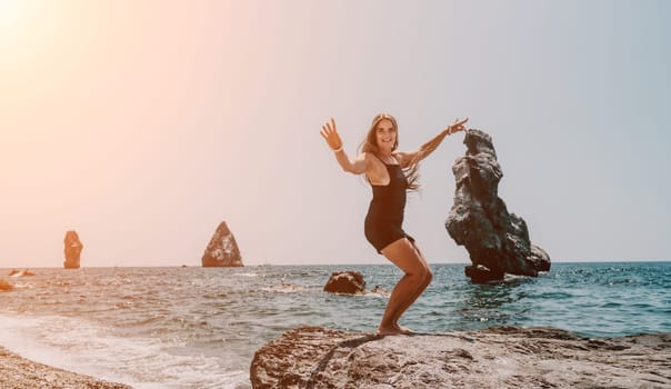 Woman travel sea. Young Happy woman in a long red dress posing on a beach near the sea on background of volcanic rocks, like in Iceland, sharing travel adventure journey