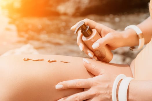 Sexy Woman in bikini apply sun protection cream on her smooth tanned legs. Skin care. Legs on the beach. Portrait of female in hat smearing moisturizing lotion. Sunblock concept.