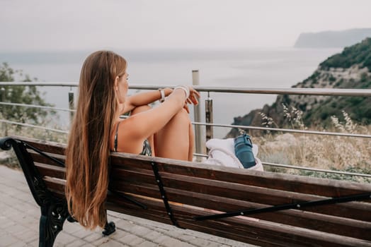 Woman travel sea. Happy tourist taking picture outdoors for memories. Woman traveler looks at the edge of the cliff on the sea bay of mountains, sharing travel adventure journey.