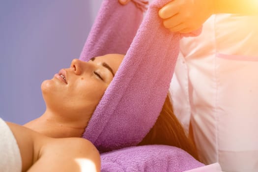 Relaxing massage. European woman getting head massage in spa salon, side view.