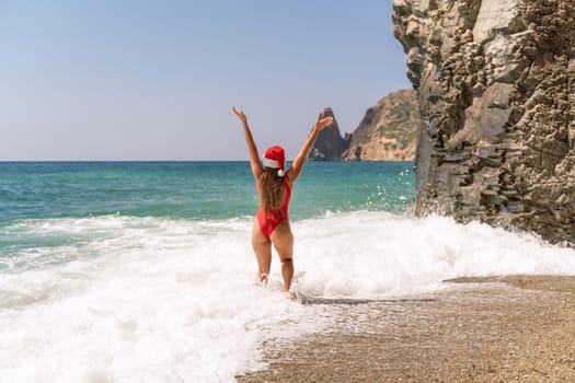 A woman in Santa hat on the seashore, dressed in a red swimsuit. New Year's celebration in a hot country