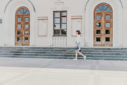 Woman staircase city. A business woman in a white shirt and denim skirt walks down the steps of an ancient building in the city.