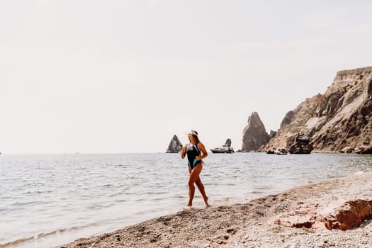 Woman beach vacation photo. A happy tourist in a blue bikini enjoying the scenic view of the sea and volcanic mountains while taking pictures to capture the memories of her travel adventure