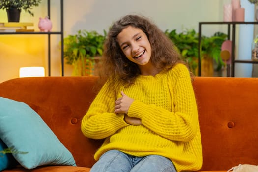 Child girl laughing out loud after hearing ridiculous anecdote, funny joke, feeling carefree amused, positive people lifestyle at home apartment. Teenager female 14-15 years kid in living room on sofa