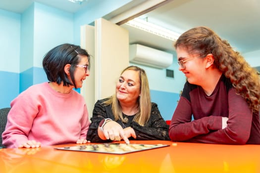 Caregiver plating board games with mental disabled women in a day center