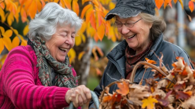 Two women are smiling while holding a rake in front of leaves