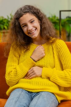 Child girl laughing out loud after hearing ridiculous anecdote, funny joke, feeling carefree amused positive people lifestyle at home apartment. Teenager 14-15 years kid in room on couch. Vertical