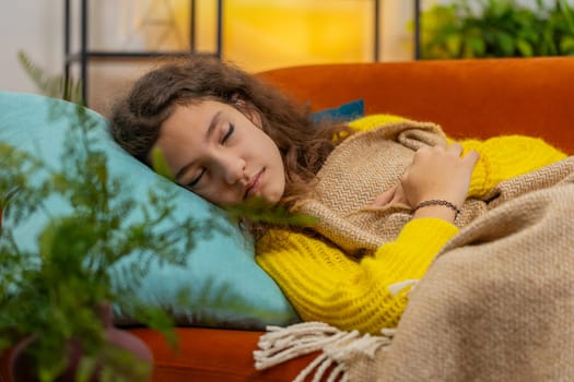 Tired 14-15 years Caucasian child girl lying down in bed taking a rest at home. Carefree teenager female kid napping falling asleep on comfortable sofa with pillows. Closed eyes enjoy daytime nap