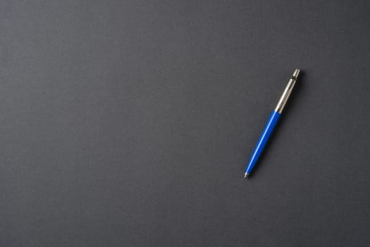 Blue plastic and metal ballpoint pen on dark gray background
