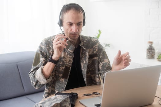 Young hispanic man army soldier using laptop sitting on table at home. High quality photo