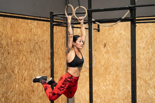 Photo with copy space of a fit woman working out with olympic rings in a gym