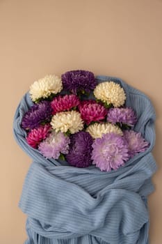 Mixed colorful flowers in cotton blue sweater. Creative minimalistic flowers. Concept of holiday celebrating present and gift. Bouquet delivery Copy space