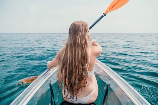 Woman in kayak back view. Happy young woman with long hair floating in transparent kayak on the crystal clear sea. Summer holiday vacation and cheerful female people having fun on the boat.