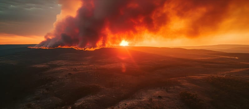 A large fire is seen from a distance as the sun sets