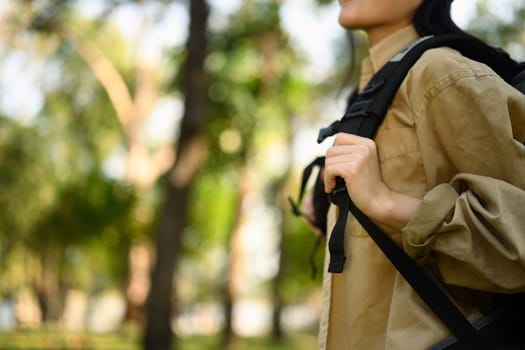 Cropped shot young woman with backpack trekking in forest. Traveling and lifestyle concept.