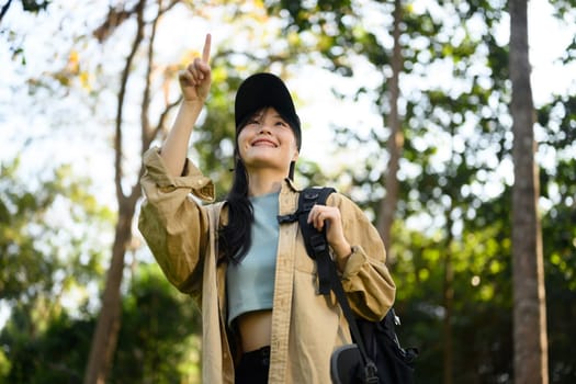 Relaxed young woman with backpack trekking in forest and enjoying nature. Traveling and lifestyle concept.