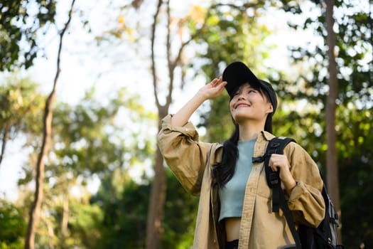 Attractive young woman with backpack trekking in forest, exploring nature. Traveling and lifestyle concept.