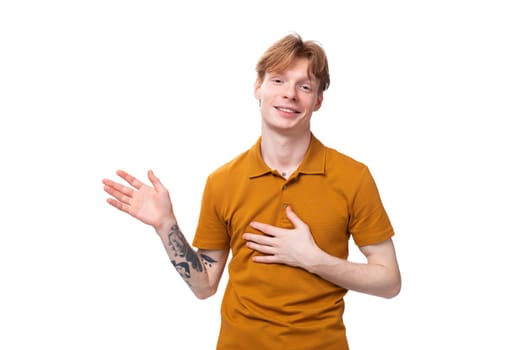 young man with red hair in orange t-shirt shows stop gesture.