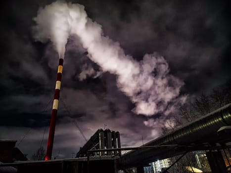 Winter night industrial landscape. Coal-fired power station with smoking chimneys against dramatic dark sky. Carbon dioxide CO2 emissions as primary driver of global climate change. Air pollution