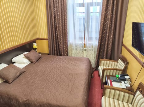 Small compact stylish bedroom in stylish soothing brown colors with double bed. Concept of small cozy bedroom or nice 3 stars hotel room