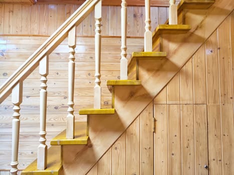 A pine wooden staircase with white balusters in cozy home. Wooden Staircase in a Rustic Interior Setting