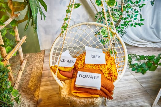 Signs with the words keep, donate, discard and fashion clothes folded in stacks in cozy room. The concept of cluttering and decluttering. Background