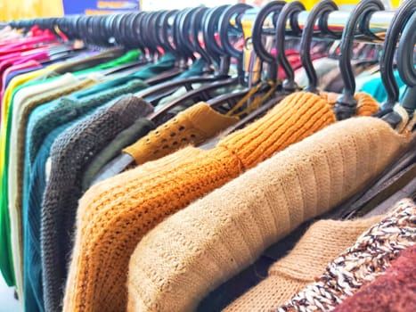 Colorful Assortment of Knitted Sweaters on Display in Bright Clothing Store. Variety of colorful sweaters hanging on a rack in a shop