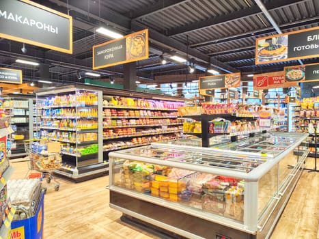 Kirov, Russia - February 22, 2024: Aisle view in grocery store with vibrant shelves full of goods. Well-Stocked Supermarket Aisles With Bright Product Displays