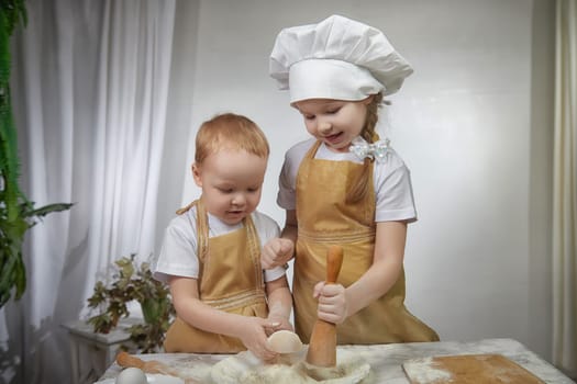 Cute oriental family with small brother and sister cooking in the kitchen on Ramadan, Kurban-Bairam, Eid al-Adha. Funny children boy and girl at cook photo shoot. Pancakes, Maslenitsa, Easter