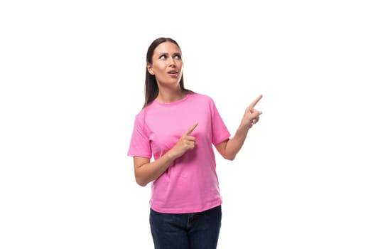 young stylish woman with straight black hair dressed in a pink t-shirt points her hand to the side.