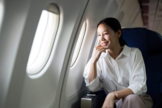 Successful asian businesswoman or female entrepreneur in a plane sits in a business class seat.