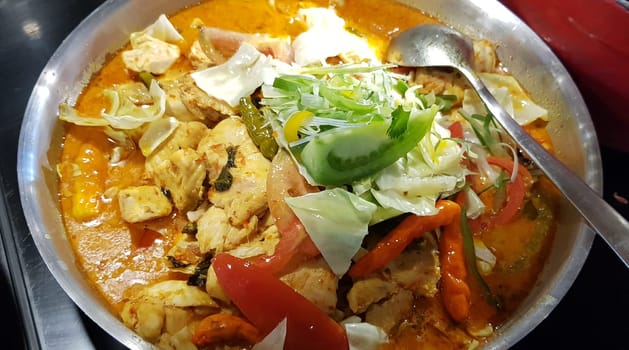 Selective focus Indonesian traditional dish mangut fish, made from smoked fish, cooked with coconut milk sauce mixed with spices, tomato, turmeric, and chillies with various seasonings