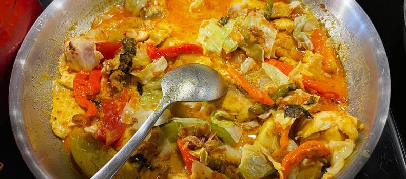 Selective focus Indonesian traditional dish mangut fish, made from smoked fish, cooked with coconut milk sauce mixed with spices, tomato, turmeric, and chillies with various seasonings