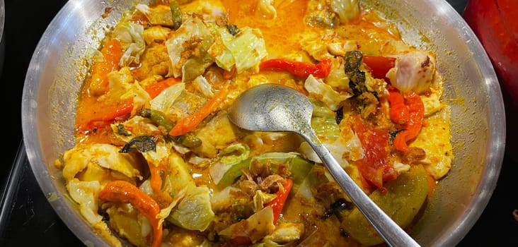Selective focus Indonesian traditional dish mangut fish, made from smoked fish, cooked with coconut milk sauce mixed with spices, tomato, turmeric, and chillies with various seasonings