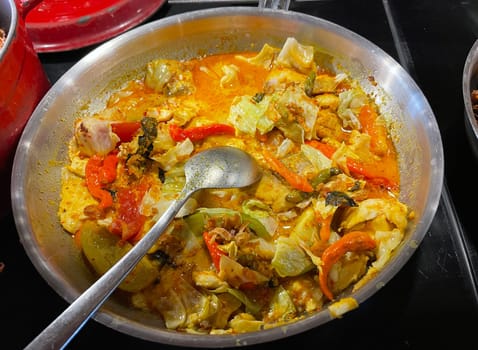 Selective focus Indonesian traditional dish mangut fish, made from smoked fish, cooked with coconut milk sauce mixed with spices, tomato, turmeric, and chillies with various seasonings