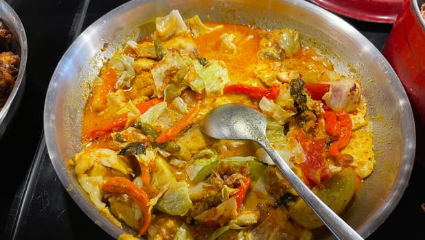Selective focus Indonesian traditional dish mangut fish, made from smoked fish, cooked with coconut milk sauce mixed with spices, tomato, turmeric, and chillies with various seasonings