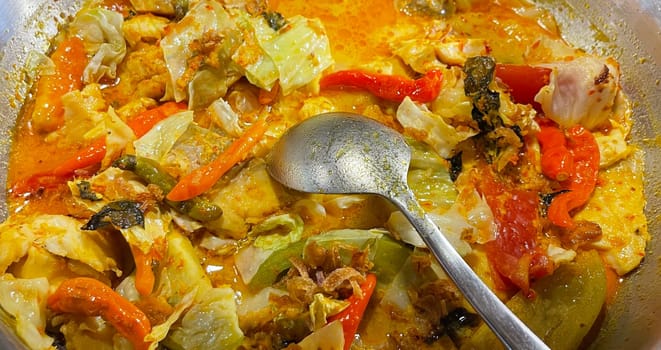 Selective focus Indonesian traditional dish mangut fish, made from smoked fish, cooked with coconut milk sauce mixed with spices, tomato, turmeric, and chillies with various seasonings