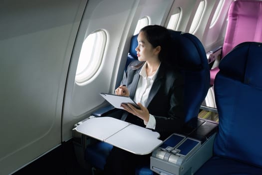 Beautiful Asian businesswoman working with tablet in aeroplane. working, travel, business concept.