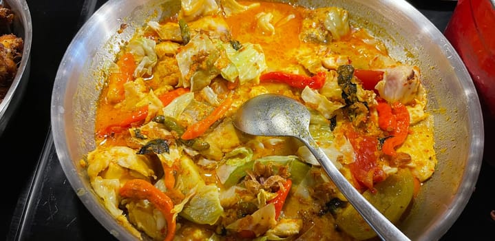 Selective focus Indonesian traditional dish mangut fish, made from smoked fish, cooked with coconut milk sauce mixed with spices, tomato, turmeric, and chillies with various seasonings