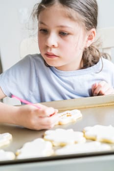 A heartwarming scene of a little girl carefully writing 'Sorry' on sugar cookies with food coloring, the cookies beautifully flooded with white royal icing.