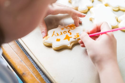 A heartwarming scene of a little girl carefully writing 'Sorry' on sugar cookies with food coloring, the cookies beautifully flooded with white royal icing.