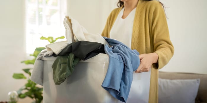 Donation, asian young woman sitting pack object at home, putting on stuff into donate box with second hand clothes, charity helping and needy people. Reuse recycle.