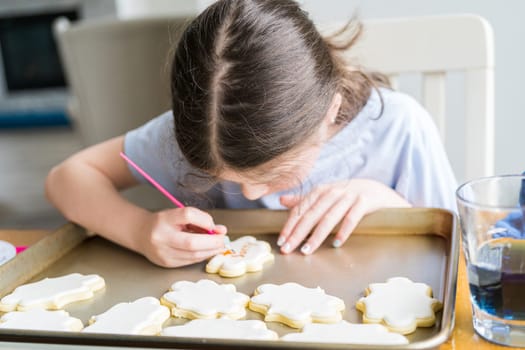 A heartwarming scene of a little girl carefully writing 'Sorry' on sugar cookies with food coloring, the cookies beautifully flooded with white royal icing.