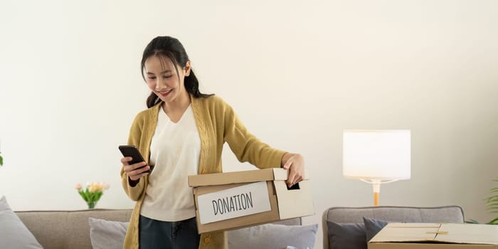 Donation concept. Woman asian holding a donate box with full of clothes. Woman holding clothes donate box. Clothes in box for concept donation and reuse recycle.