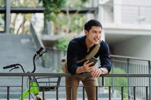 asian young businessman use smart phone while commuting in city. Eco friendly.