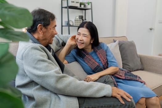 Older couples sit and chat and head over each other relaxed and happy on sofa at home on weekday in comfortable.