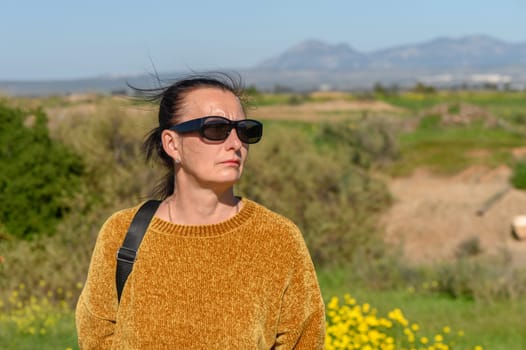 woman in a yellow sweater and glasses against a background of mountains 2