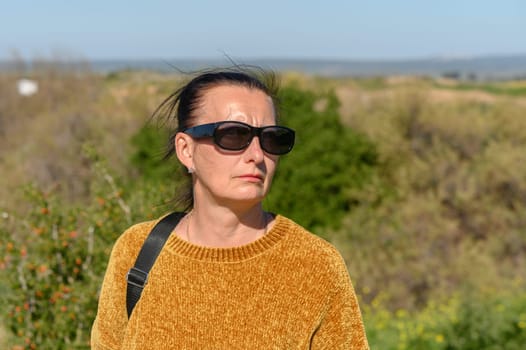 woman in a yellow sweater and glasses against a background of mountains 3