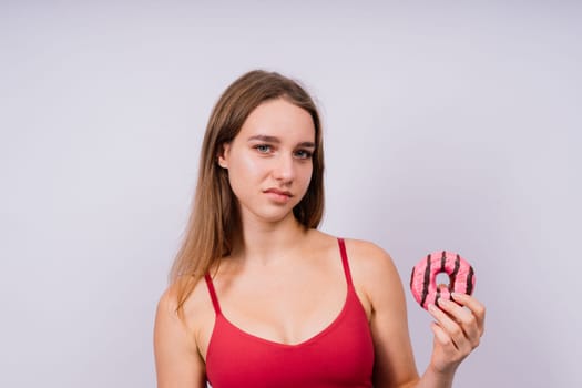 Young cute sport woman eating donut cake in studio background